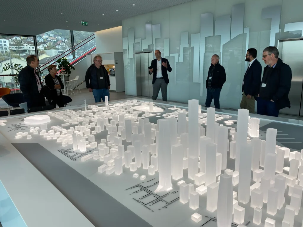 Grupo de profisisonais observa maquete urbana em escala no Innovation Lab da Schindler, em Ebikon, Suíça, durante apresentação sobre gestão inteligente do fluxo de pessoas em edifícios